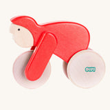 A red Bajo Velo cyclist wooden toy. This wooden toy is part of a wide range of push along toys available at Babipur.