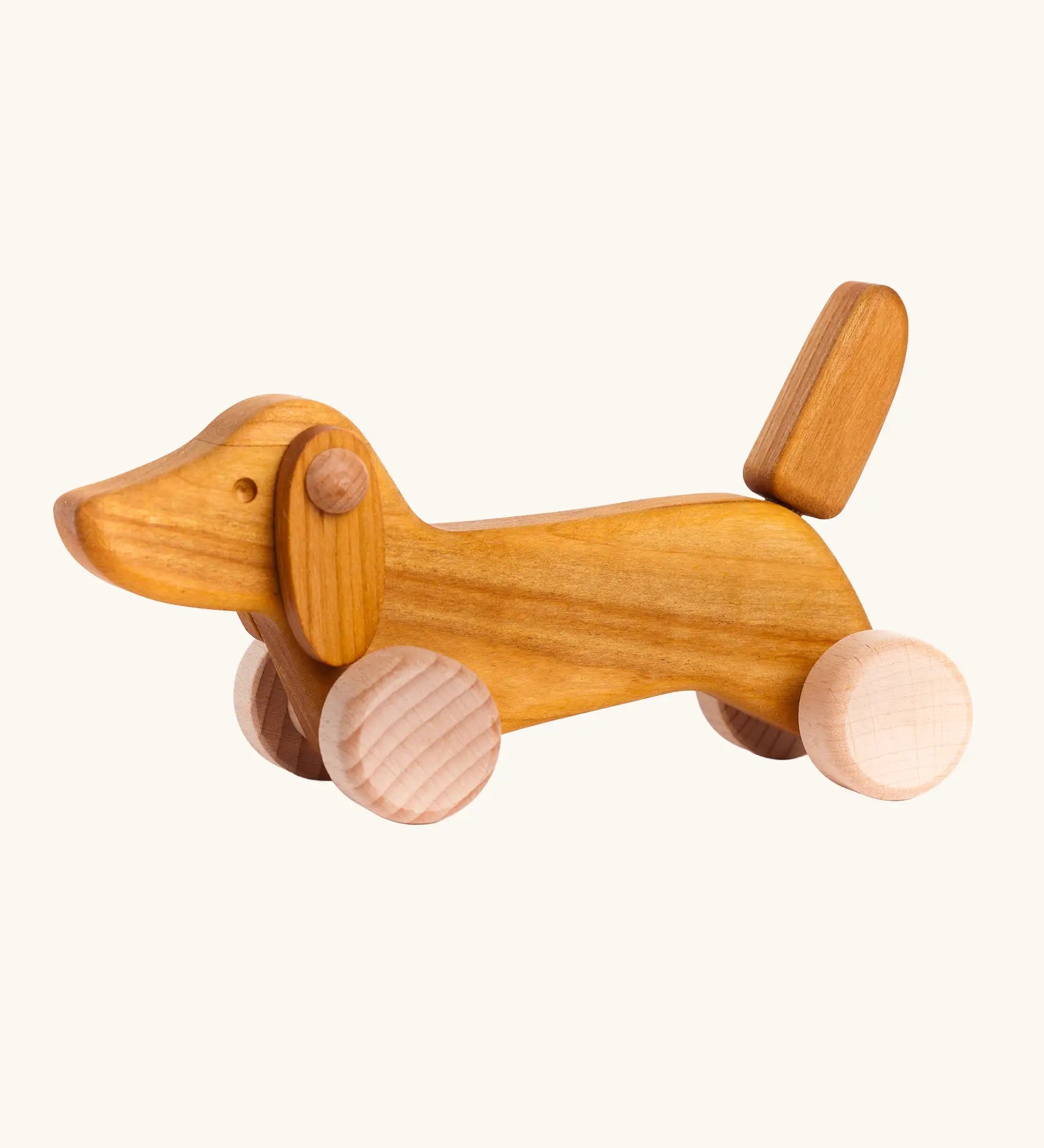 Bajo Natural Dachshund Puppy in unpainted natural wood, a push-along toy for toddlers with floppy ears, an upright tail, and four wooden wheels, available online from Babipur.