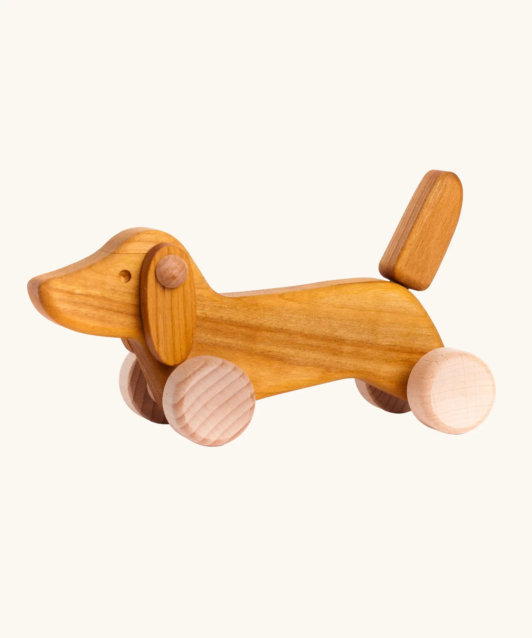 Bajo Natural Dachshund Puppy in unpainted natural wood, a push-along toy for toddlers with floppy ears, an upright tail, and four wooden wheels, available online from Babipur.