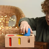 A child playing with the Bajo Deep And Shallow Sorter wooden toy placed on a small wooden table. These heirloom quality toys by Bajo are part of a wide range of wooden toys available here at Babipur. 