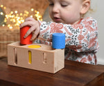 A child playing with the Bajo Deep And Shallow Sorter wooden toy placed on a small wooden table. These heirloom quality toys by Bajo are part of a wide range of wooden toys available here at Babipur. 