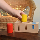 A child playing with the Bajo Deep And Shallow Sorter wooden toy placed on a small wooden table. These heirloom quality toys by Bajo are part of a wide range of wooden toys available here at Babipur. 