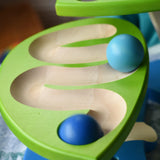 Close up of blue wooden balls rolling down one of the leaves on the Bajo Dewdrop, Coloured wooden ball run.