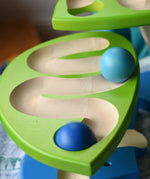 Close up of blue wooden balls rolling down one of the leaves on the Bajo Dewdrop, Coloured wooden ball run.