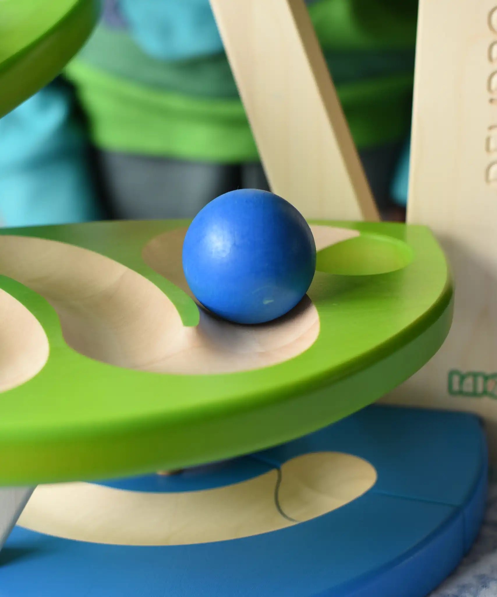 Close up of a blue wooden ball rolling down the track on the Bajo Dewdrop, Coloured wooden ball run.