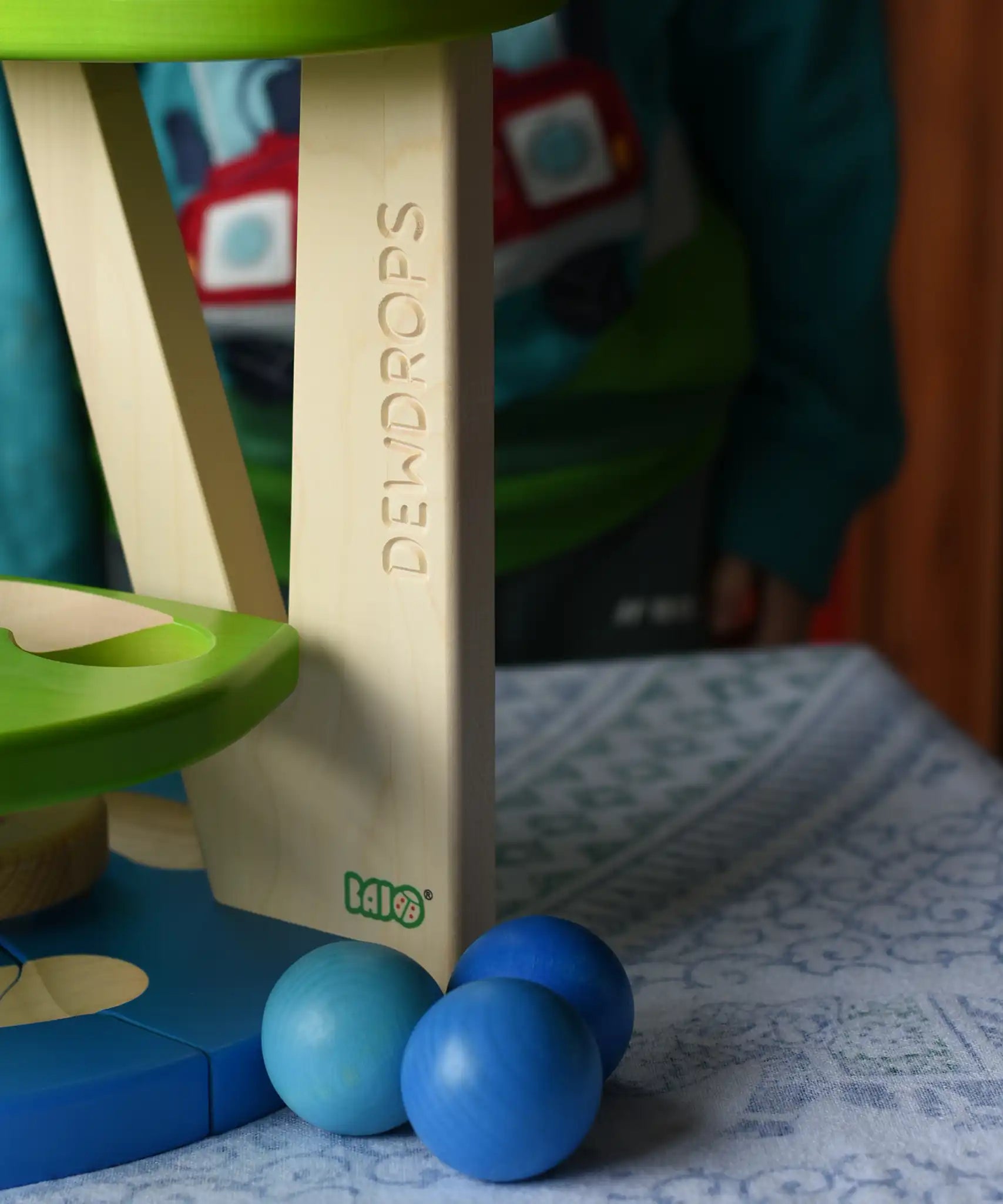 Three blue wooden balls paced besides the Bajo Dewdrop, Coloured wooden ball run.
