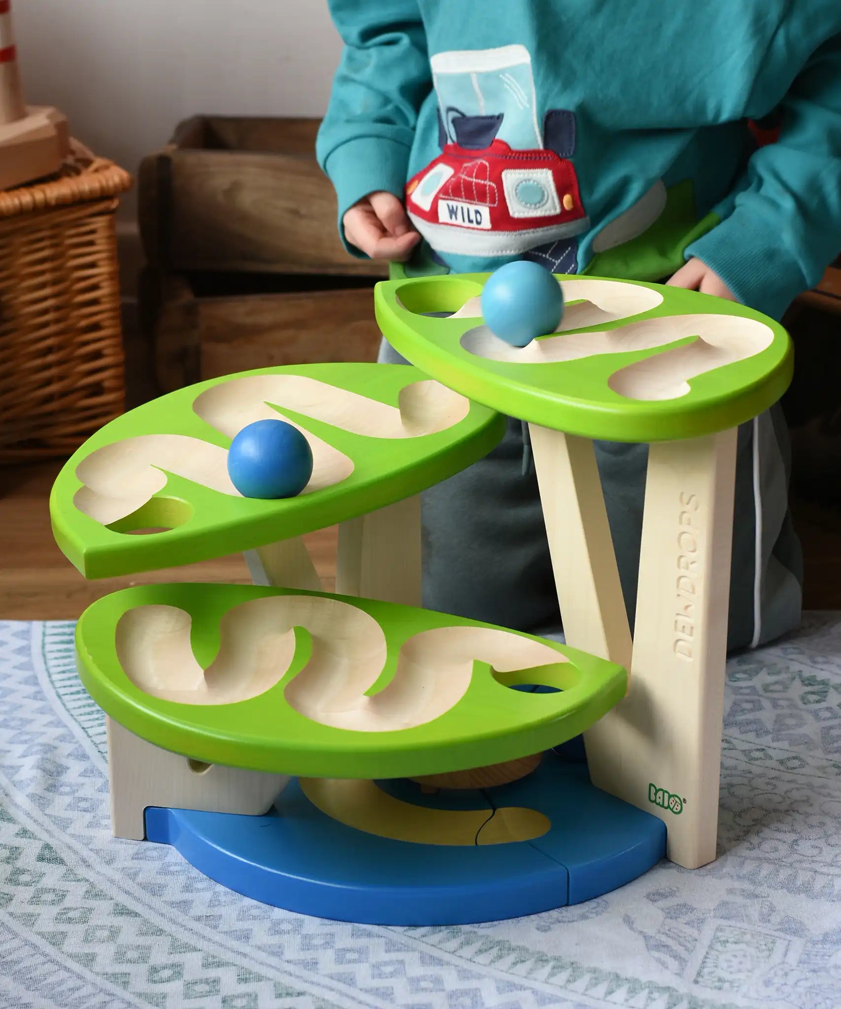 Child playing with the Bajo Dewdrop, Coloured wooden ball run.