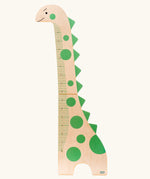 Bajo dinosaur measuring growth chart. A natural wooden dinosaur decorated with green dots and spikes down it's neck and back.
