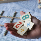 Wooden number and symbol tiles from the Bajo toys wooden easy maths learning set in an child's hand. 