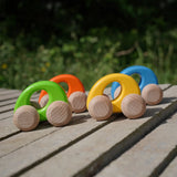 A group of Bajo handmade wooden ellipse toy cars standing on a concrete surface