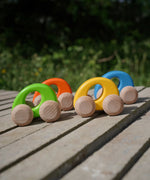 A group of Bajo handmade wooden ellipse toy cars standing on a concrete surface