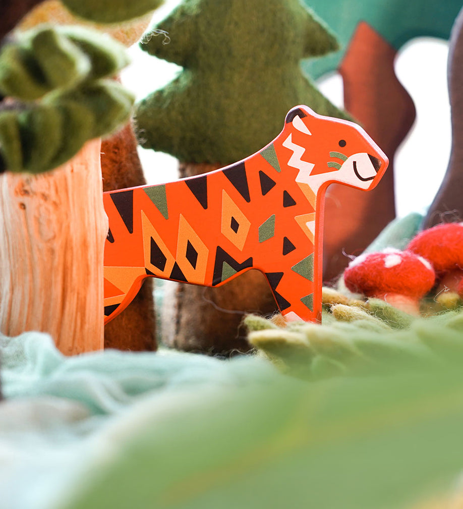 A Bajo tiger endangered wooden toy animal figure placed in a small world play scene with trees and green coloured cloths. These heirloom quality toys by Bajo are part of a wide range of wooden toys available here at Babipur. 