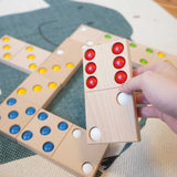 An adult's hand holding a domino from the Bajo gaint dominos set. These heirloom quality toys by Bajo are part of a wide range of wooden toys available here at Babipur. 