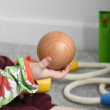 A large wooden ball in a child's hand. This ball is included in the Bajo fellow skittles set. These heirloom quality toys by Bajo are part of a wide range of wooden toys available here at Babipur.