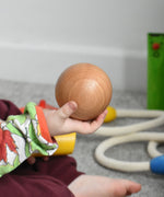 A large wooden ball in a child's hand. This ball is included in the Bajo fellow skittles set. These heirloom quality toys by Bajo are part of a wide range of wooden toys available here at Babipur.