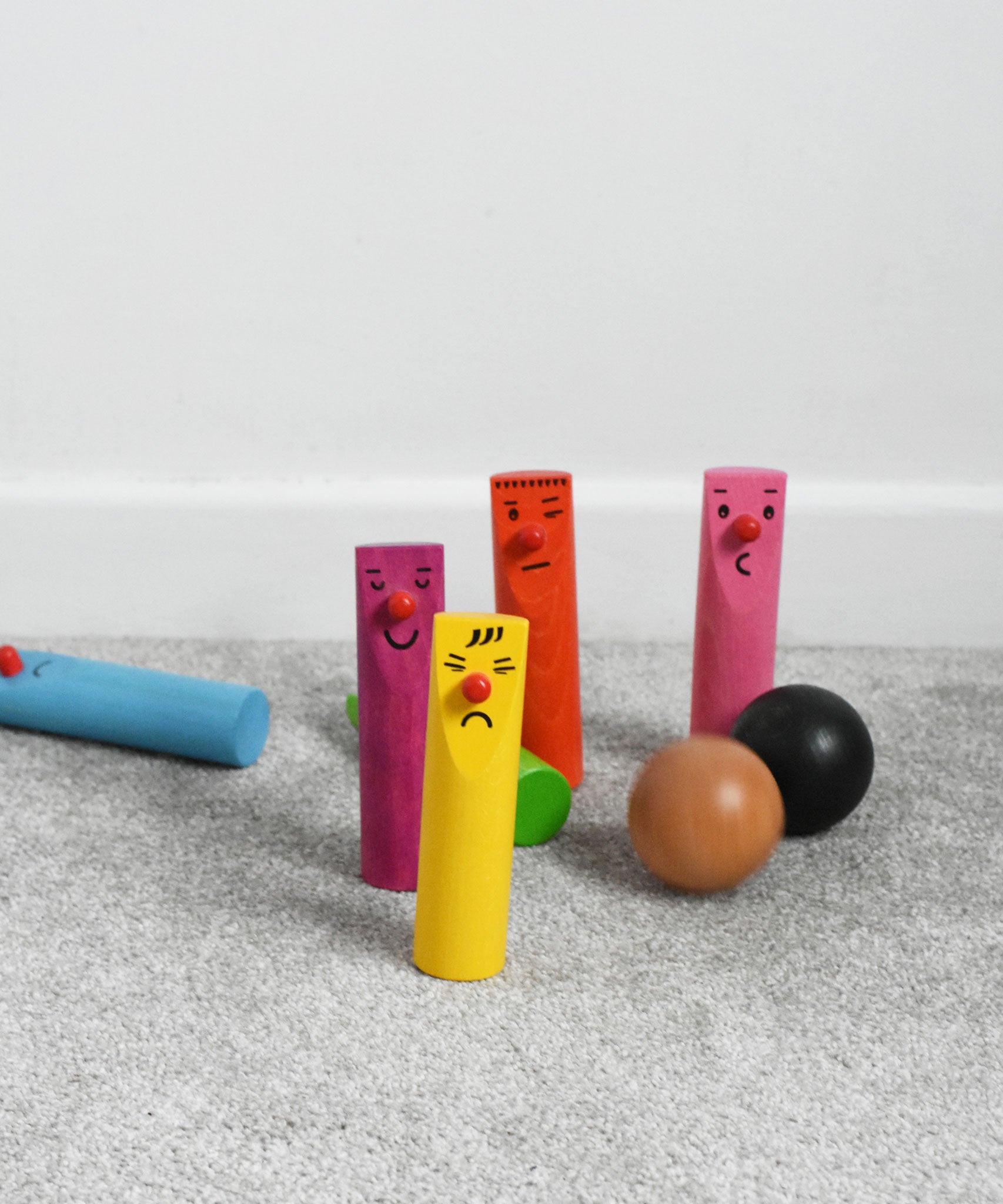 Bajo Fellow Skittles wooden toy game. Six coloured wooden skittles decorated with faces with red noses. The set comes with two wooden balls.  These heirloom quality toys by Bajo are part of a wide range of wooden toys available here at Babipur.