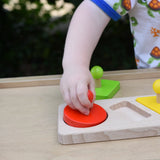 Child playing with the Bajo figures shapes sorting board, placing the red circle piece into the wooden base frame.