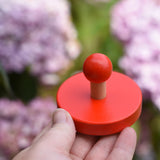 Red circles pieces from the Bajo figures shapes sorting board in an adult's hand