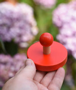 Red circles pieces from the Bajo figures shapes sorting board in an adult's hand