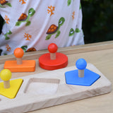 Bajo figures shapes sorting board placed on a Miri with some pieces taken out and placed besides the base frame.