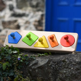 Bajo figures shapes sorting board placed on a stone wall outdoors.