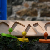 Bajo figures shapes sorting board base placed on a stone wall with the shapes taken out of the frame.