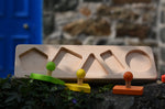 Bajo figures shapes sorting board base placed on a stone wall with the shapes taken out of the frame.