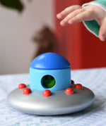 A child's hand reaching for the Bajo Alien Flying Saucer.