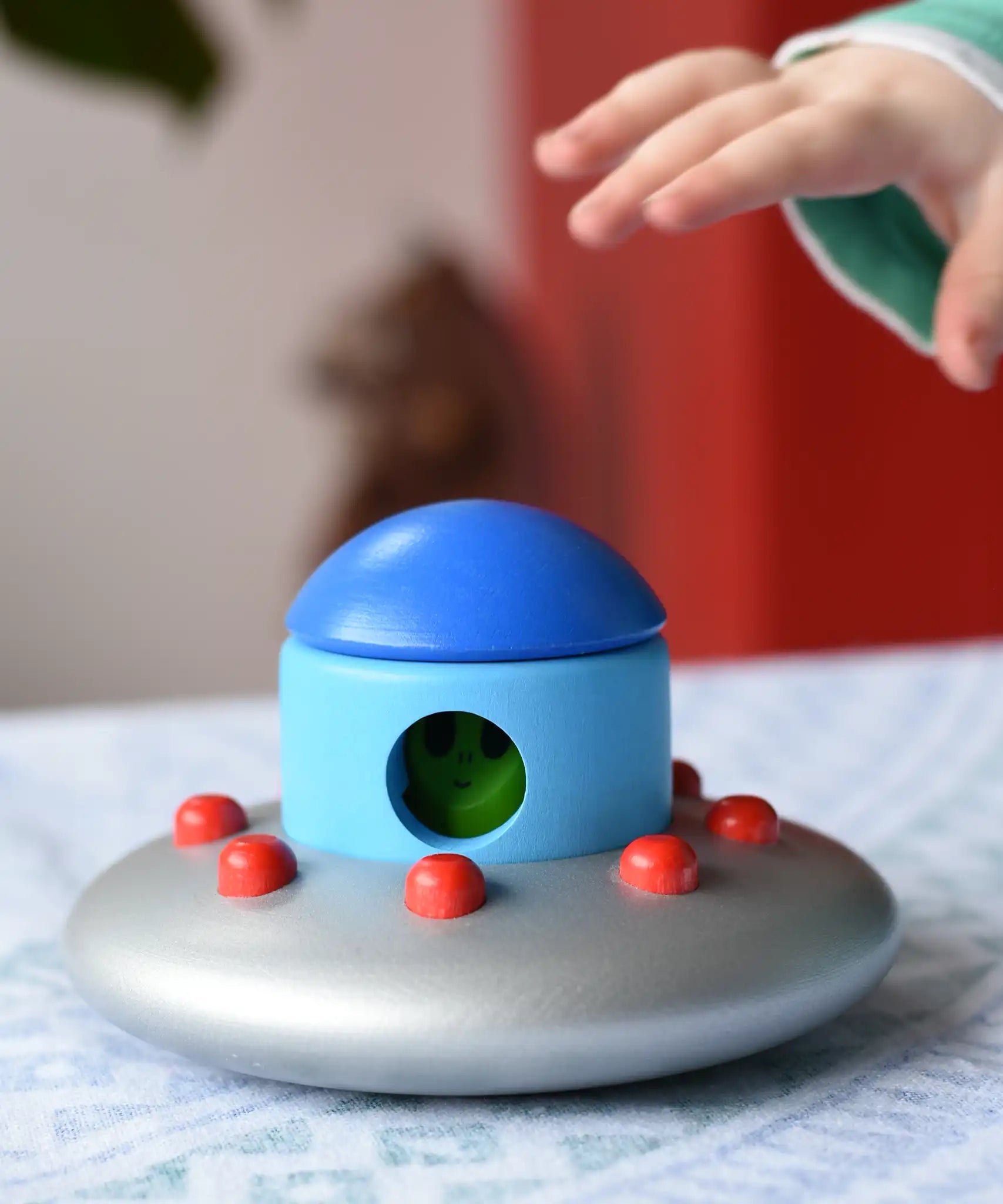 A child's hand reaching for the Bajo Alien Flying Saucer.