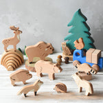 The Bajo Wild Animals Forest Set set up in a small world play scene with a Grimm's mini rainbow Holztiger fir tree in the background