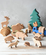 The Bajo Wild Animals Forest Set set up in a small world play scene with a Grimm's mini rainbow Holztiger fir tree in the background