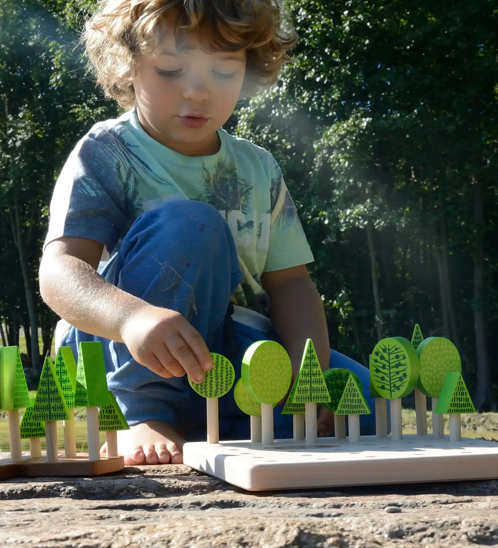 Child playing with Bajo's forest central park set on a stone surface 