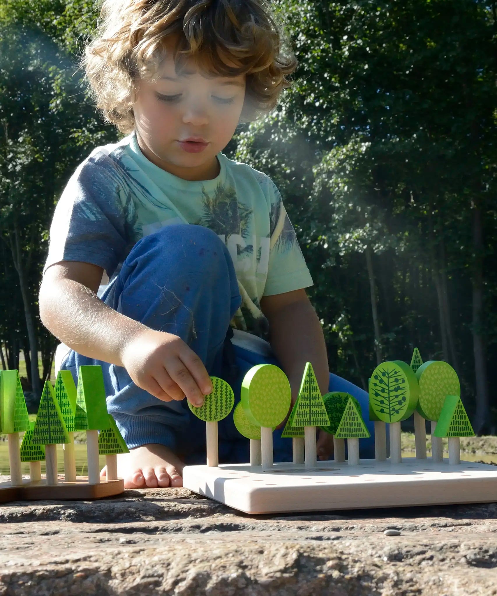 Child playing with Bajo's forest central park set on a stone surface 