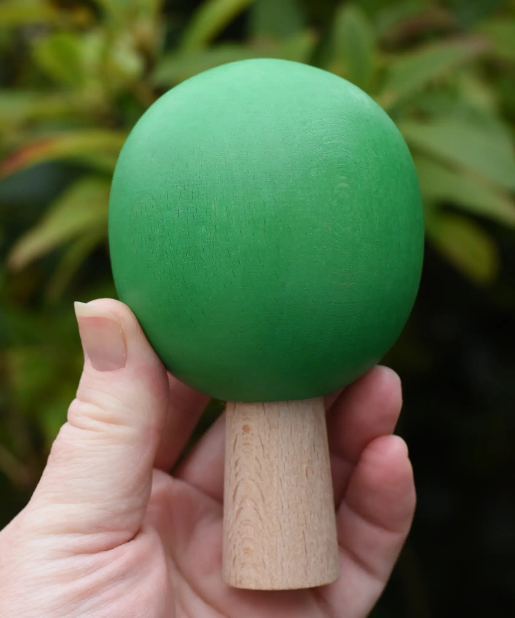 Large green sphere tree from the Bajo green forest tree set in a adult's hand.