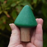 Small green conical tree from the Bajo green forest tree set in a adult's hand.