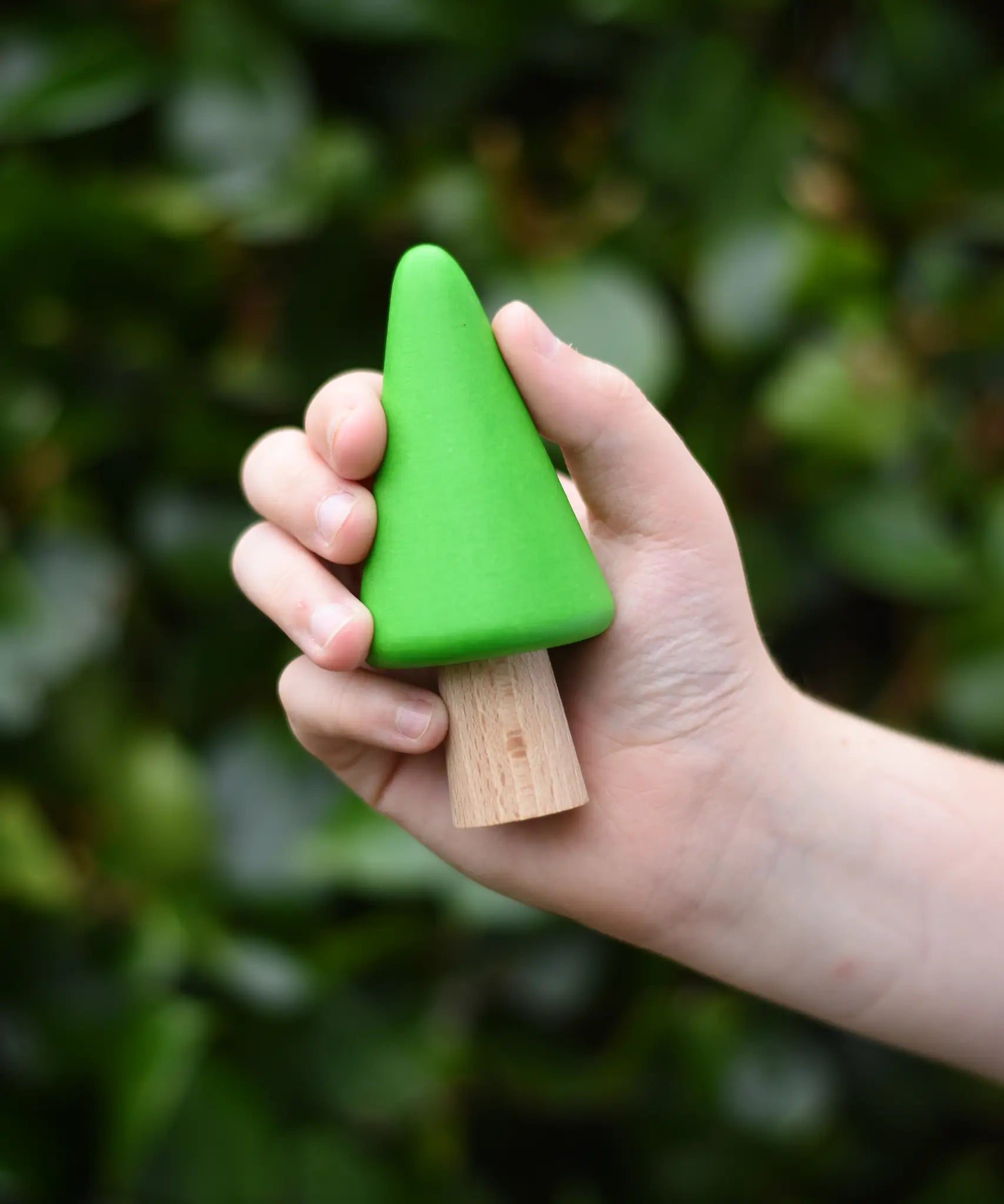 Light green conical tree from the Bajo green forest tree set in a child's hand.