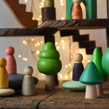 Bajo green forest tree set - 5 wooden trees in a set of 5 placed on a wooden surface amongst Bajo pebbles with Grapat animal crew Nins with a Magic Wood adventure playground in the background.
