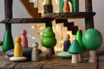 Bajo green forest tree set - 5 wooden trees in a set of 5 placed on a wooden surface amongst Bajo pebbles with Grapat animal crew Nins with a Magic Wood adventure playground in the background.
