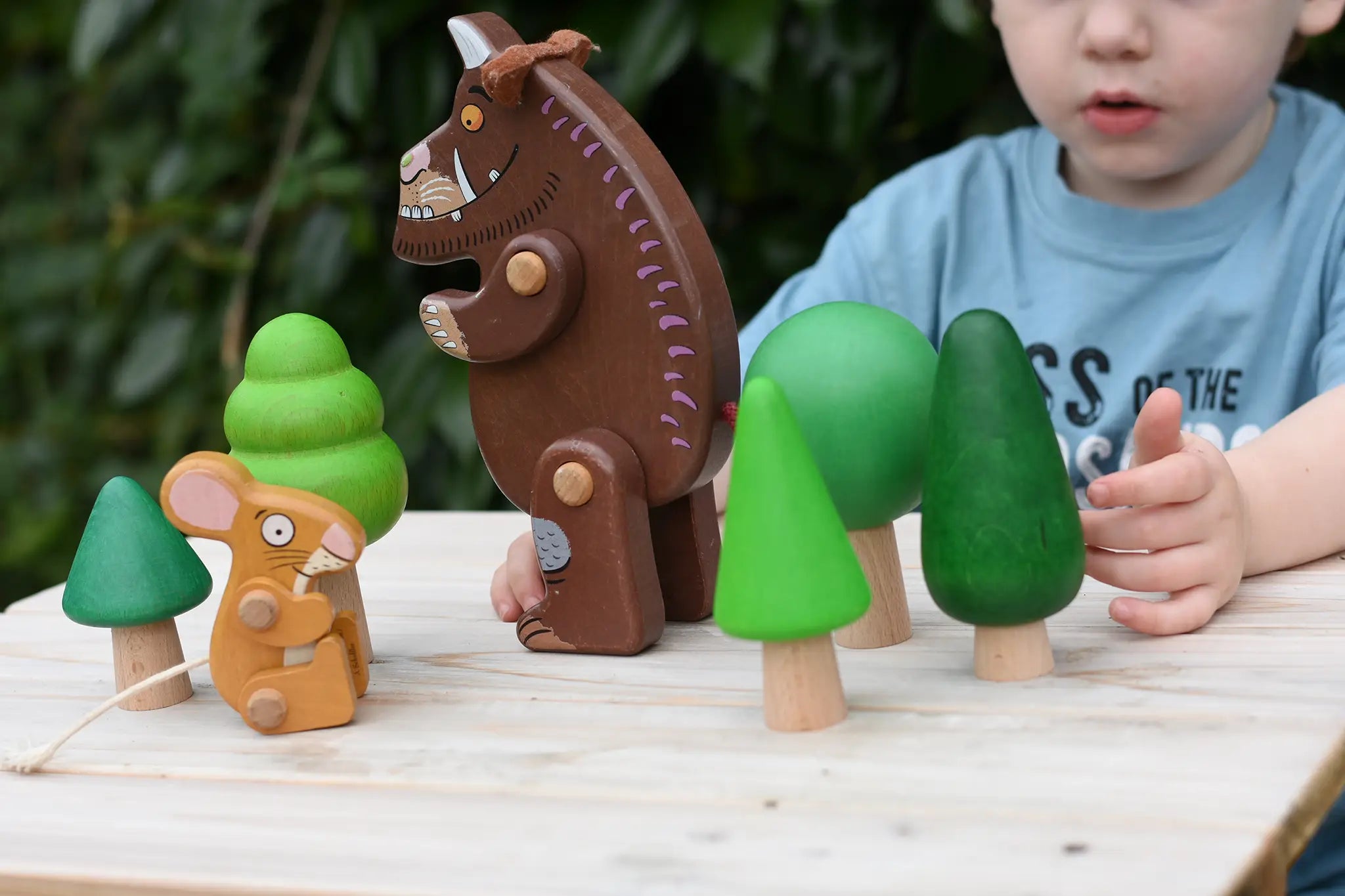 Child playing with the Bajo green forest tree set and Gruffalo and mouse character figures. 