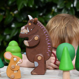Child playing with the Bajo green forest tree set and the Gruffalo and mouse character figures. 
