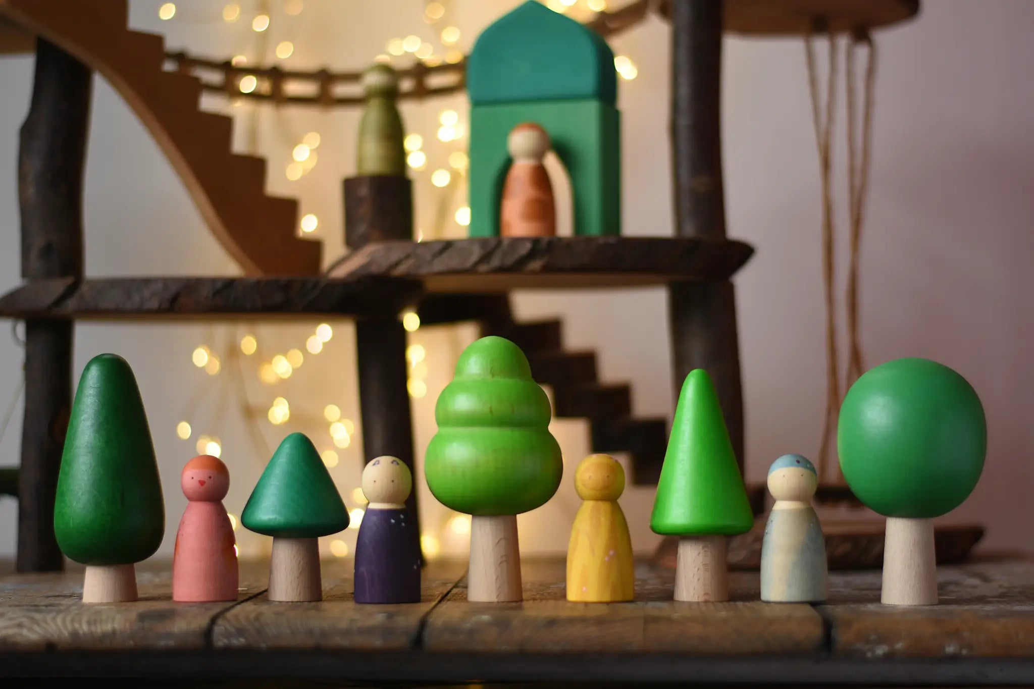 Bajo green forest tree set figures lined up next to Grapat animal crew wooden peg dolls. Magic Wood adventure playground in eh background. 