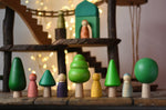 Bajo green forest tree set figures lined up next to Grapat animal crew wooden peg dolls. Magic Wood adventure playground in eh background. 