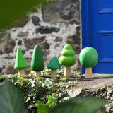 Bajo green forest tree set of wooden toy figures placed on a stone wall outdoors.