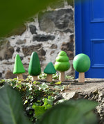 Bajo green forest tree set of wooden toy figures placed on a stone wall outdoors.