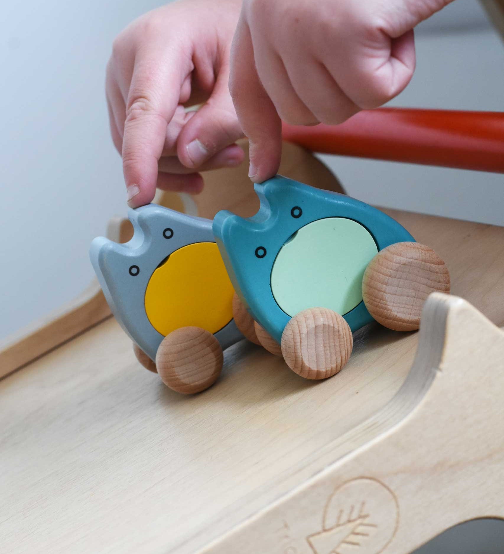 A child's hand holding two Bajo wooden push along ghost toys on a Triclimb Miri slide ready to let go of them and let them slide down.
These heirloom quality wooden toys are part of a wide range available here at Babipur.