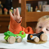 A child playing with  Bajo Pull-Back Caterpillar Toy and grasshopper toys.  These heirloom quality toys by Bajo are part of a wide range of wooden toys available here at Babipur.