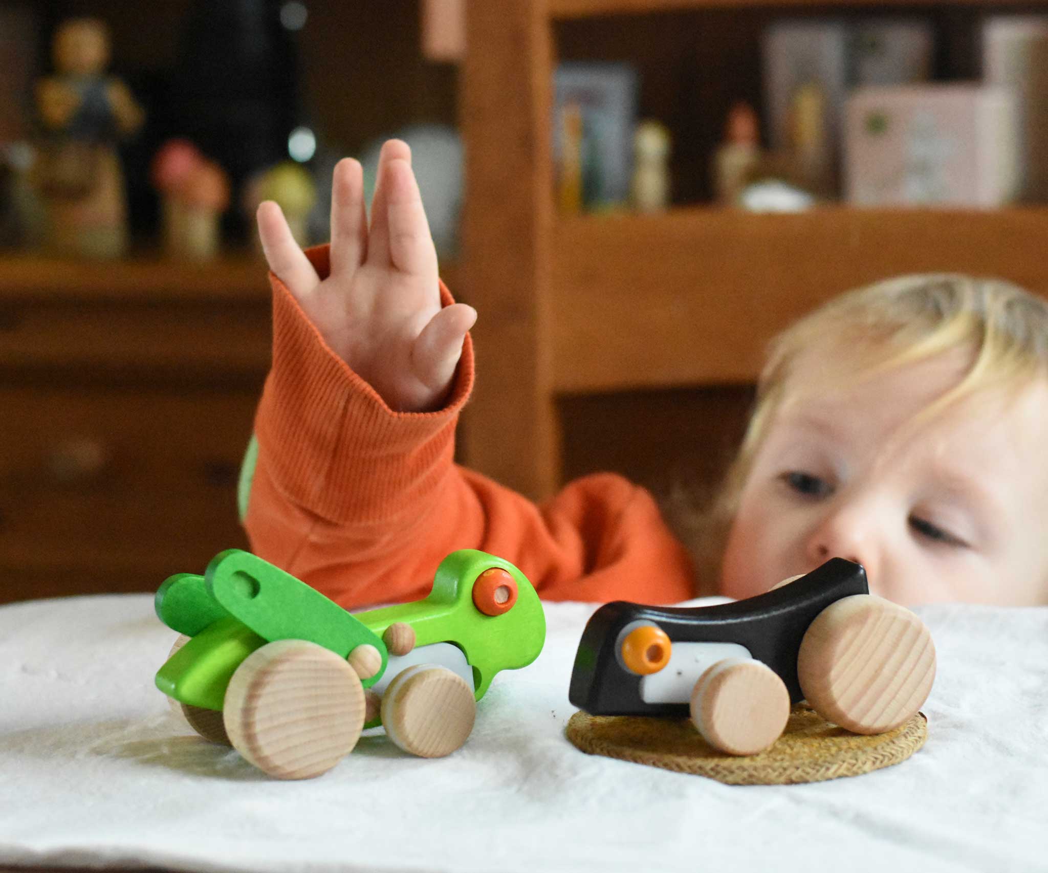 A child playing with  Bajo Pull-Back Caterpillar Toy and grasshopper toys.  These heirloom quality toys by Bajo are part of a wide range of wooden toys available here at Babipur.