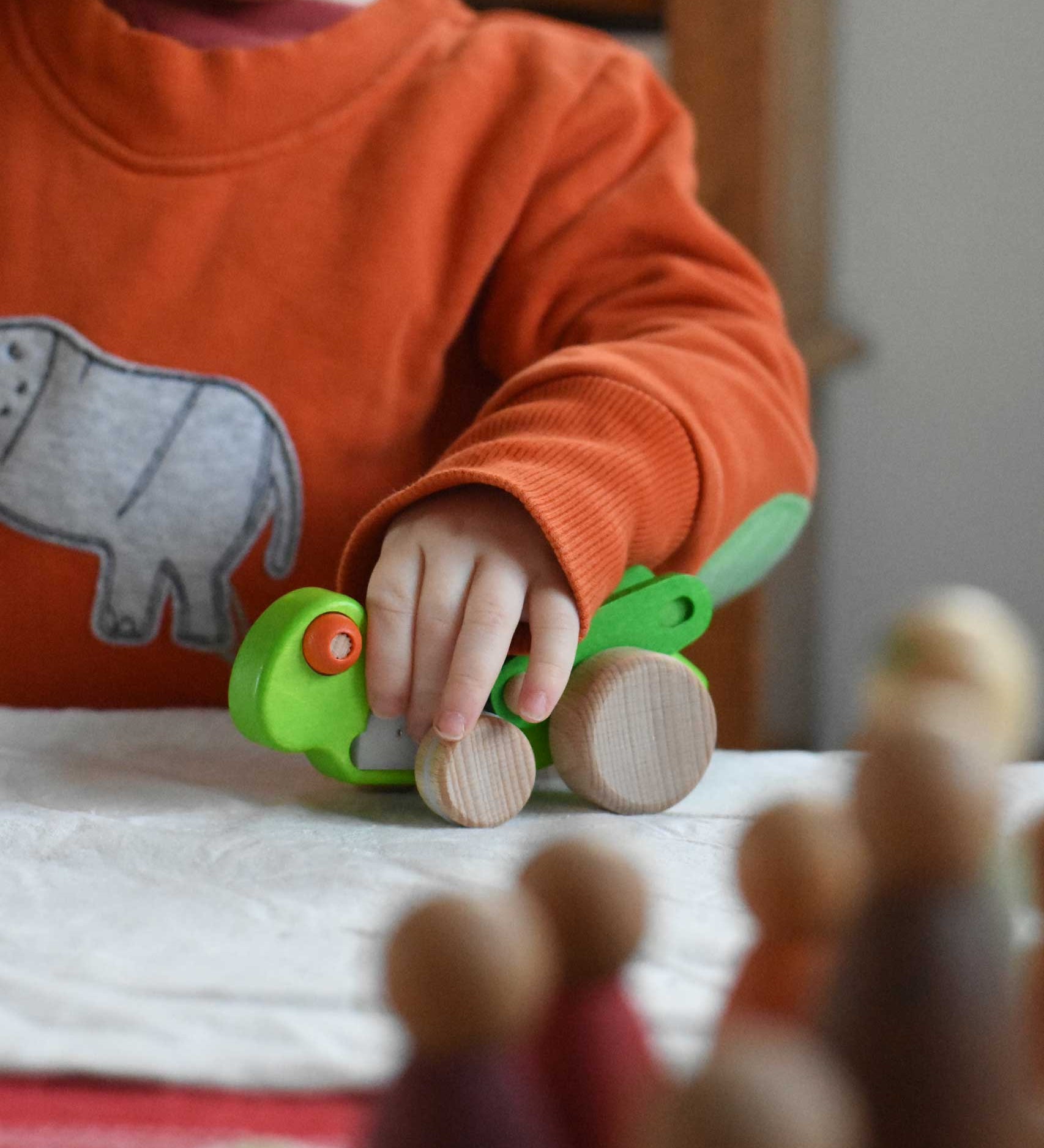 A child playing with the Bajo green Grasshopper wooden toy. These heirloom quality toys by Bajo are part of a wide range of wooden toys available here at Babipur.