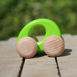 Bajo handmade wooden ellipse toy car in green with unpainted wheels standing on a concrete surface