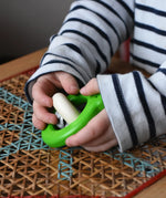 Child playing with the Bajo green Frog Rattle wooden baby toy in the Babipur playroom